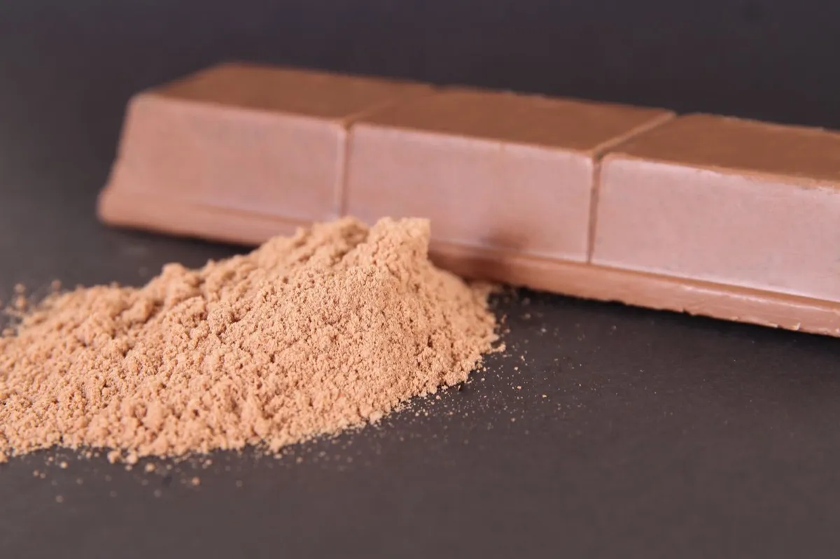 Dark chocolate bar and cocoa powder on a dark surface